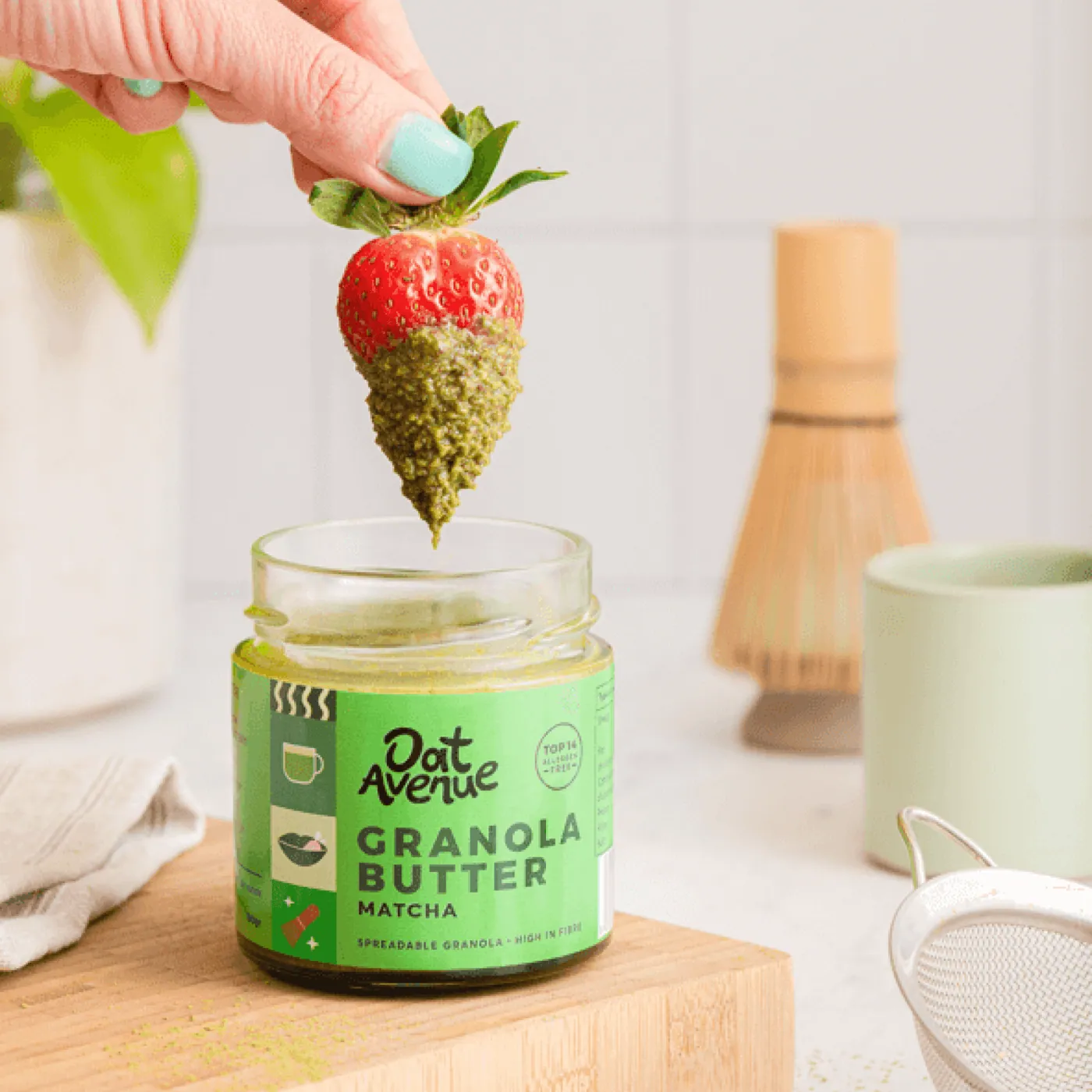 A strawberry dipped into Matcha granola butter