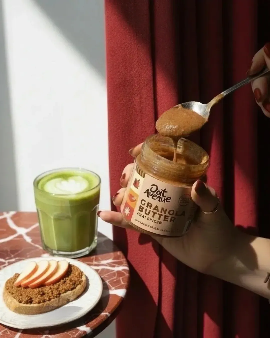 A spoonful of Chai Spiced granola butter lifted from the jar, next to a matcha latte and toast